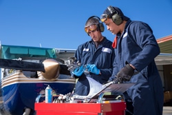 Two Male Airplaine Mechanics Working on a Small Plane