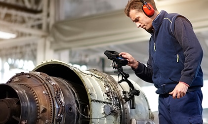 Aerospace technician inspecting equipment, supporting recruitment for skilled workers in aviation and industrial sectors.