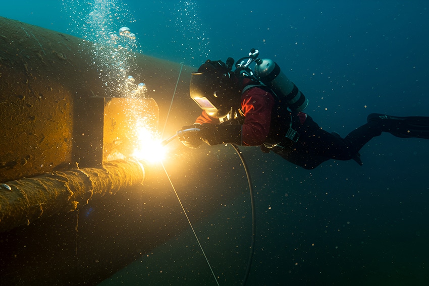 Underwater welder using specialized equipment to repair an underwater pipeline in Canada.